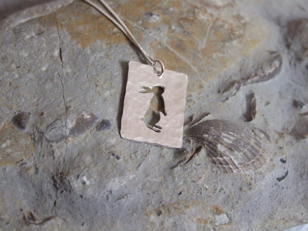 Silver rabbit pendant: A Curious bunny stands up to look around at the world on a background of textured sterling silver.